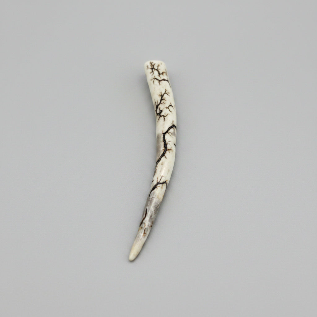 other side view of the Natural deer antler comfort tine polished and decorated with strikes on a gray background