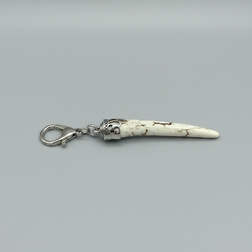 Deer antler tip with dark strike and polished keychain with silver clasp on a gray background