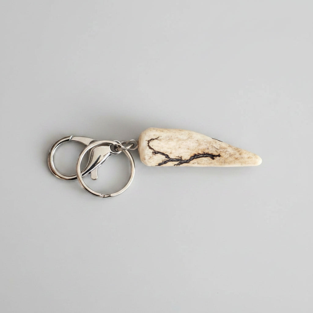 Deer antler tip with dark strike keychain with silver clasp on a gray background