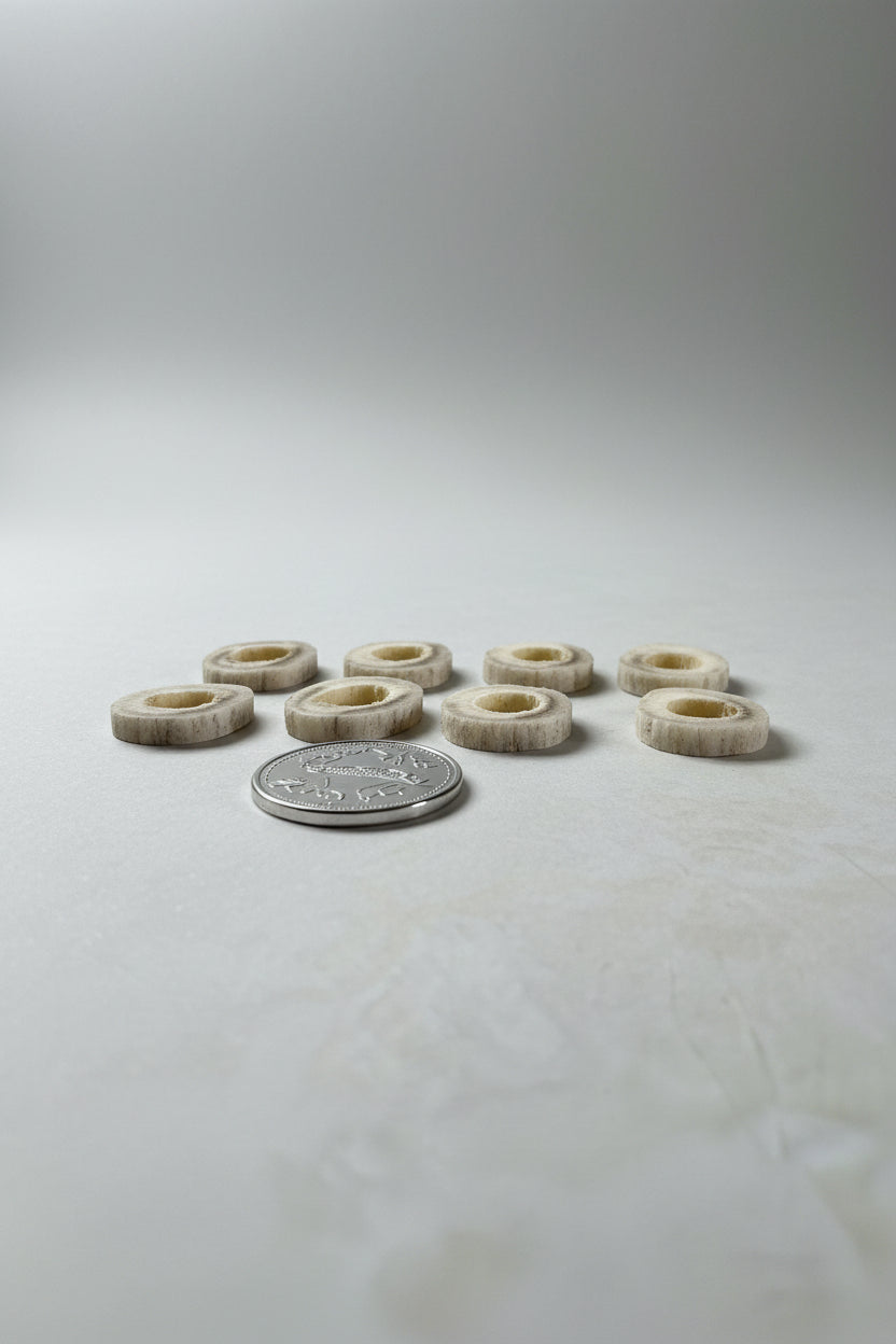Side view of 8 deer antler slice, with a hole on the middle on a gray background