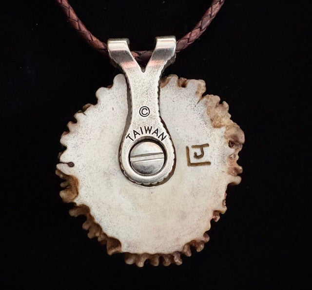 Back view of Tortoiseshell turtle pendant on a leather cord against a black background
