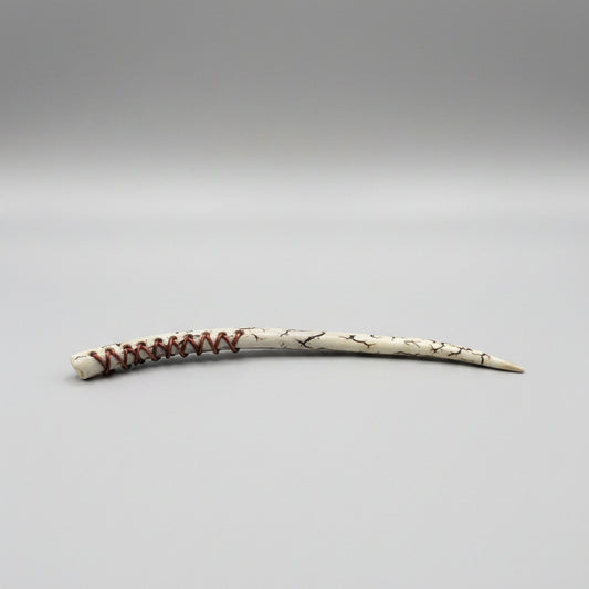 Long, thin wand made of a long antler tip with decorative leather patterns on a gray background