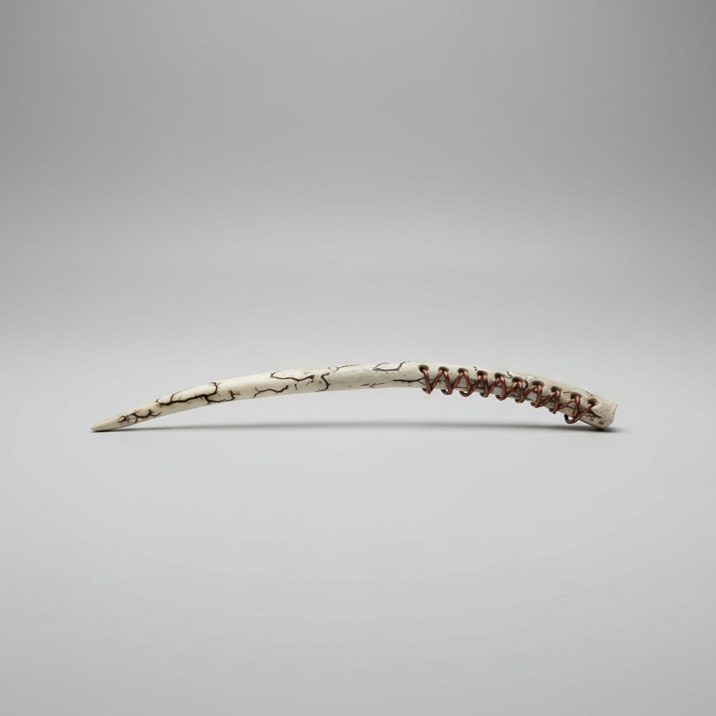 Long, thin wand made of a long antler tip with decorative leather patterns on a gray background