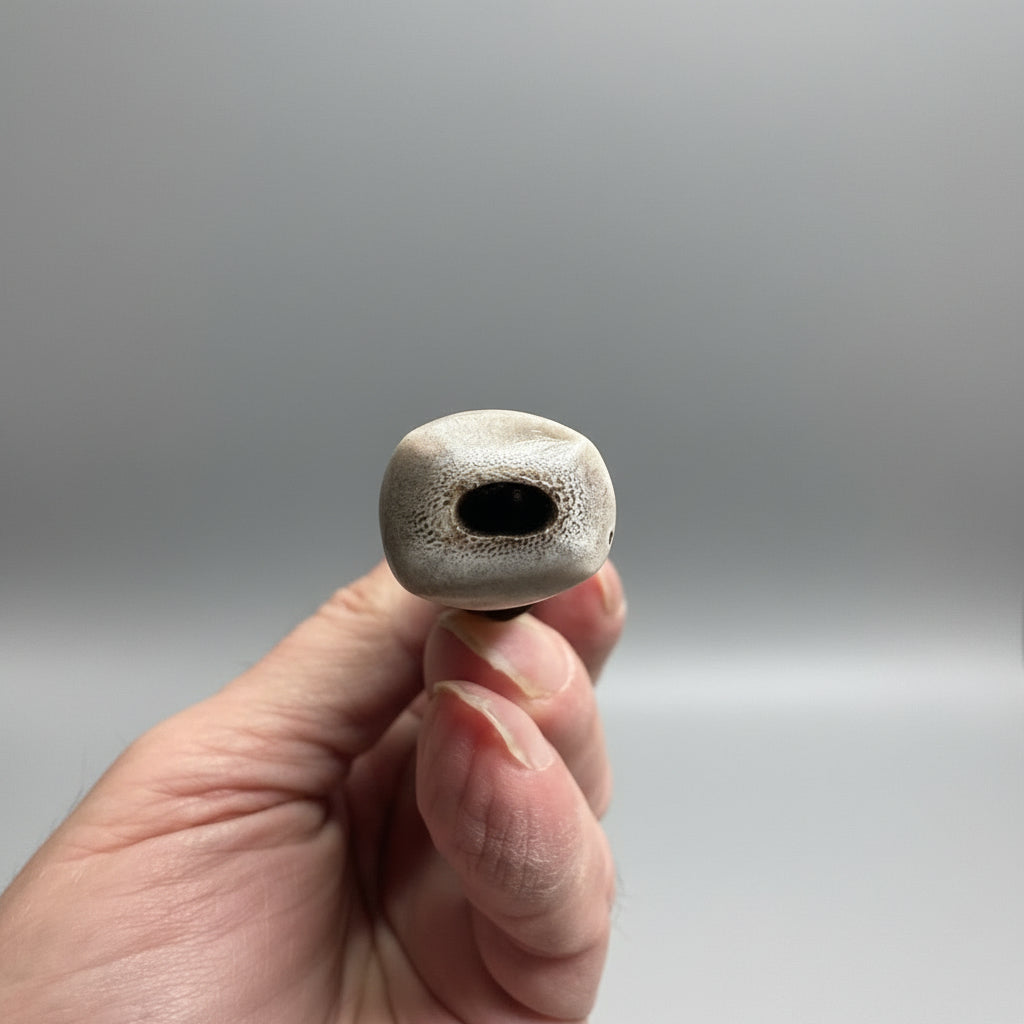 End part of a wand made of a long antler tip with decorative leather patterns on a gray background