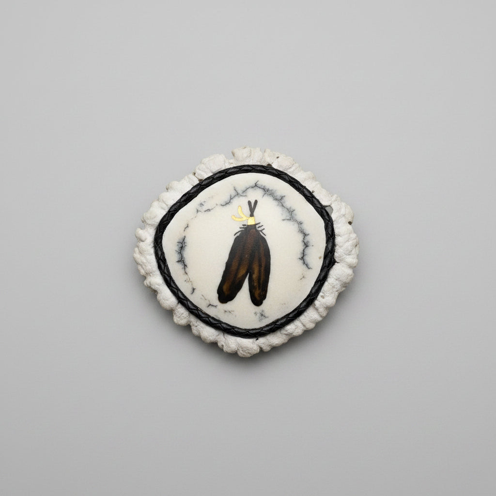 cornet from the end of a elk antler with 2 feather inlayed and polished on a gray background
