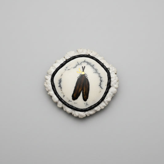cornet from the end of a elk antler with 2 feather inlayed and polished on a gray background