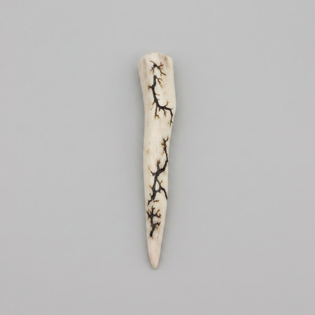 Natural deer antler comfort tine polished and decorated with strikes on a gray background