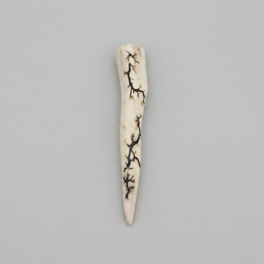 Natural deer antler comfort tine polished and decorated with strikes on a gray background