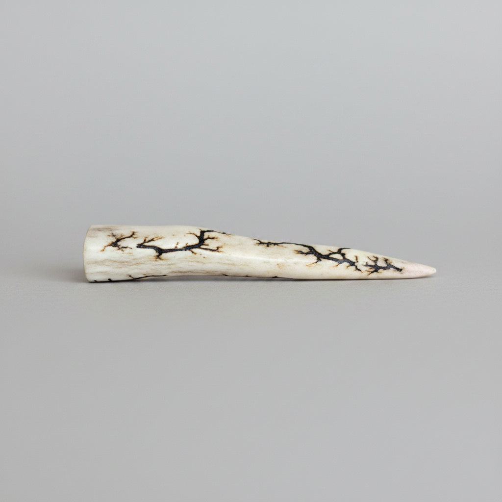 Side view of the Natural deer antler comfort tine polished and decorated with strikes on a gray background