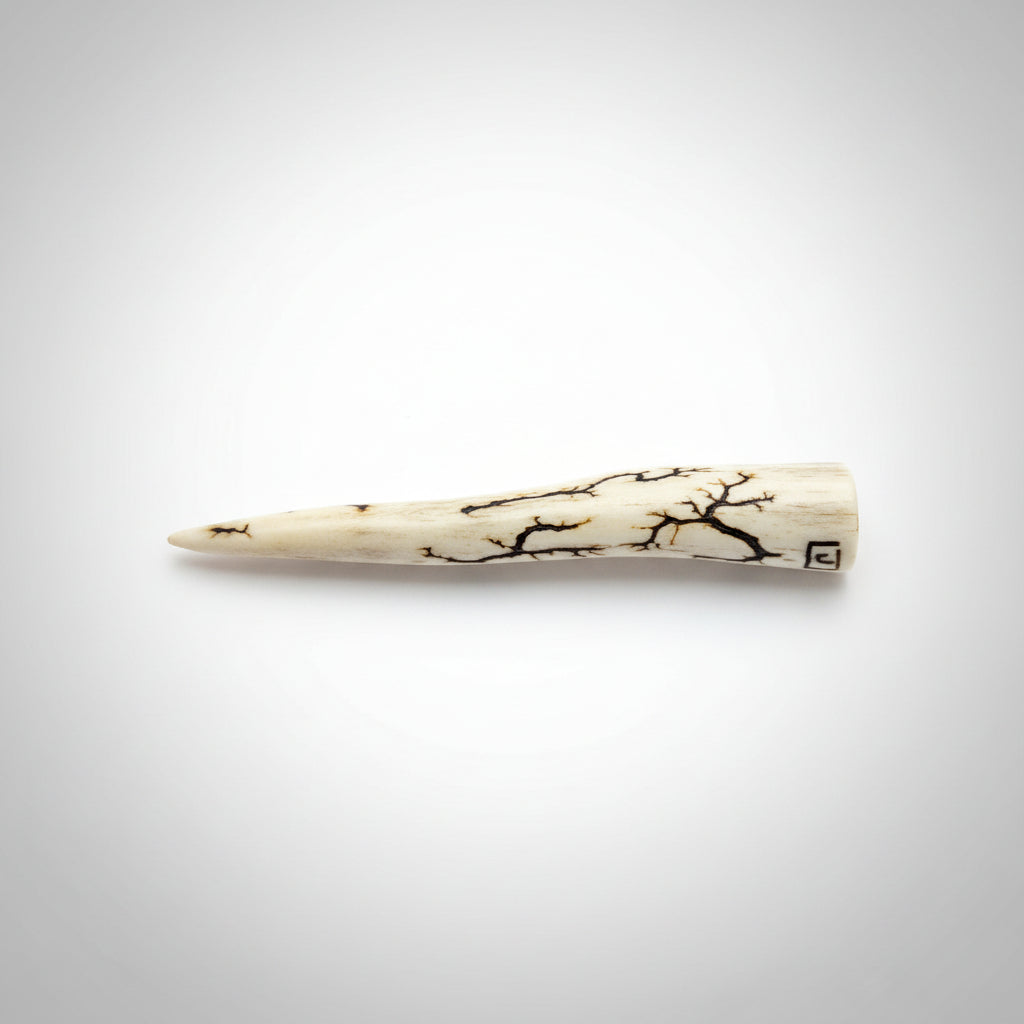 Bottom view of the Natural deer antler comfort tine polished and decorated with strikes on a gray background
