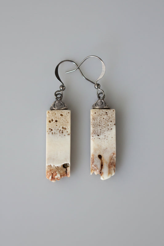 Pair of earrings with rectangular, textured antler on a black background
