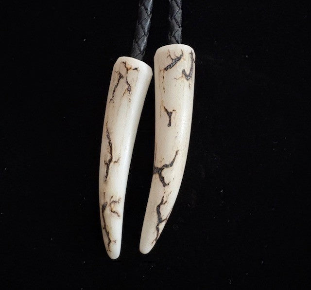 natural antler tips at the end of the cords of the bolo tie on a black background
