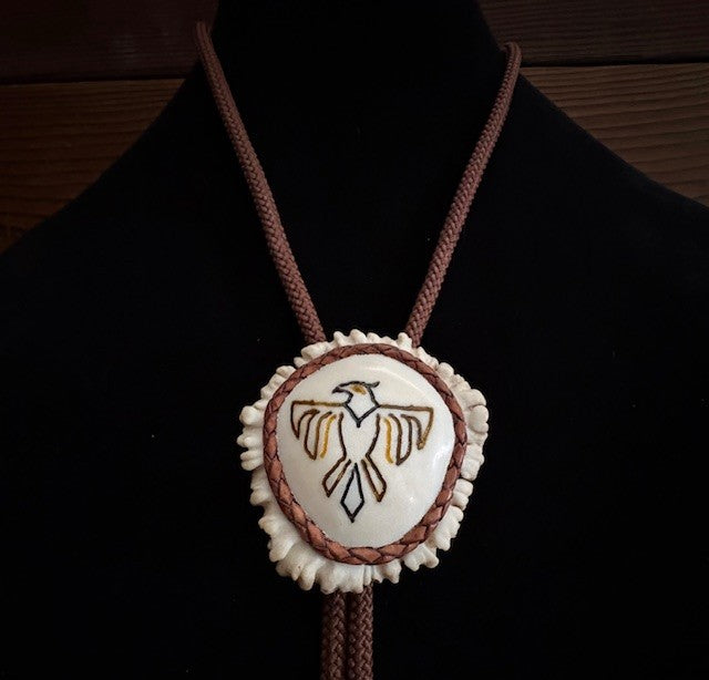 Bolo tie with a thunderbird design on a black background