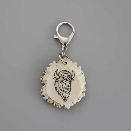 Deer antler keychain with a engraved buffalo on a gray background