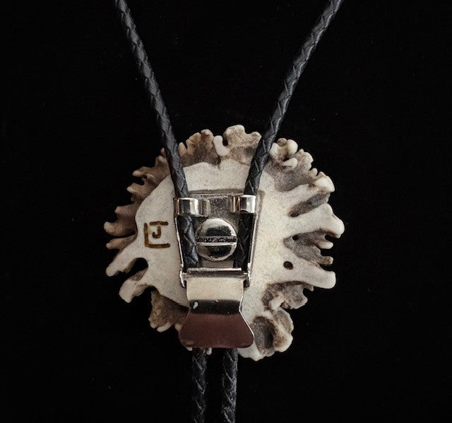 Close-up of the back of the bolo tie with a artist signature on a black background