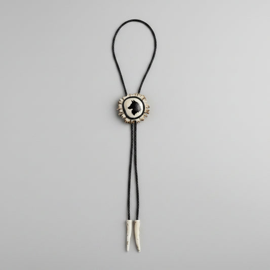 deer antler bolo tie with a wolf head carved and inlaid on  gray background
