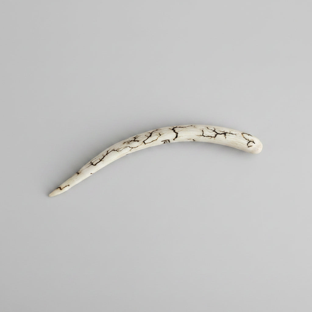 Side view of the natural deer antler hair pin polished on a gray background