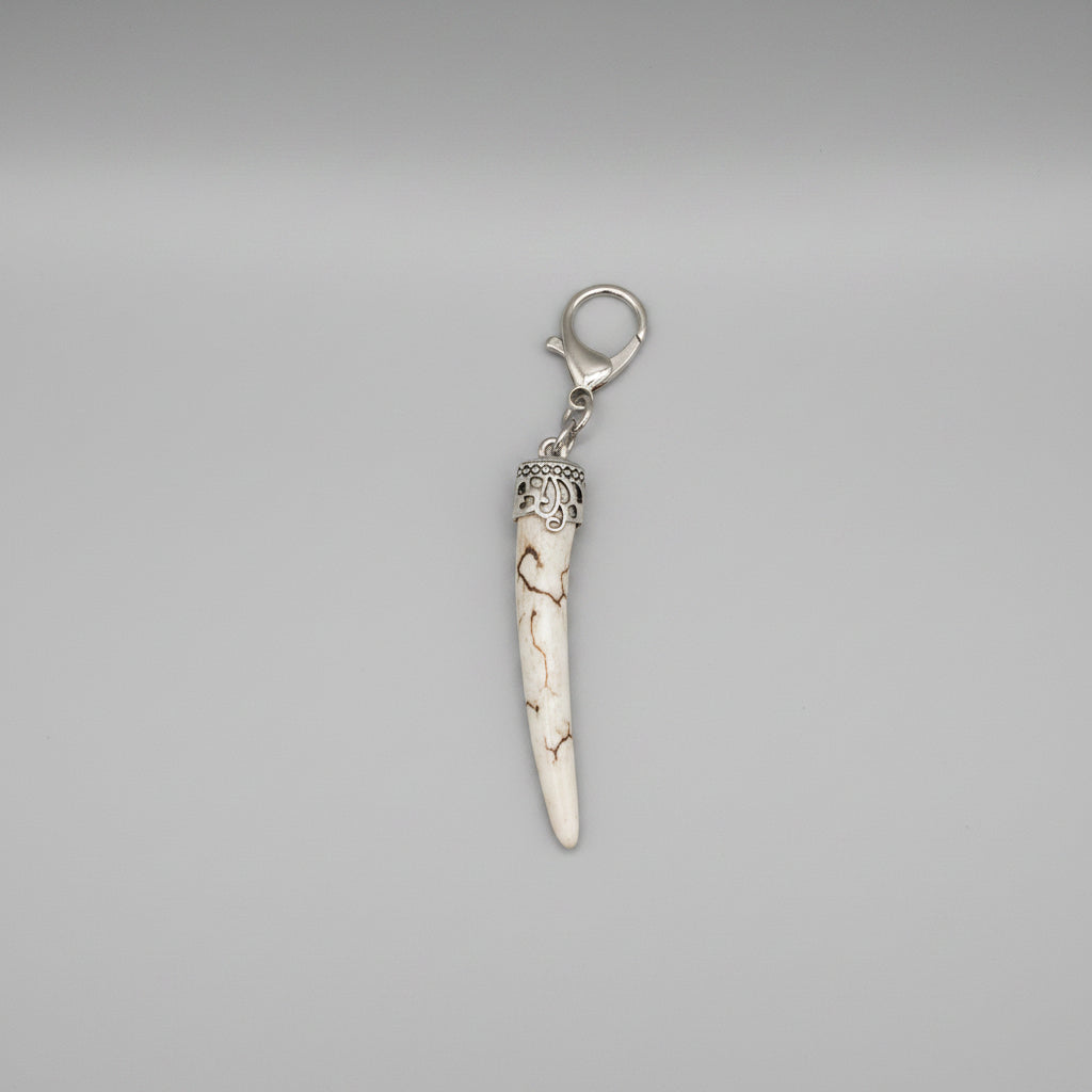 Deer antler tip with dark strike and polished keychain with silver clasp on a gray background