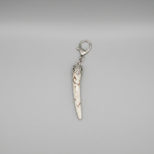 Deer antler tip with dark strike and polished keychain with silver clasp on a gray background