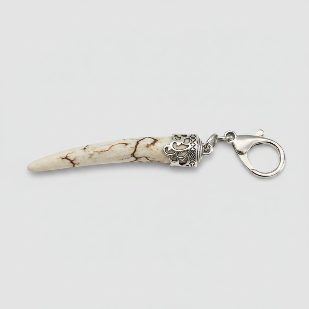 Deer antler tip with dark strike and polished keychain with silver clasp on a gray background