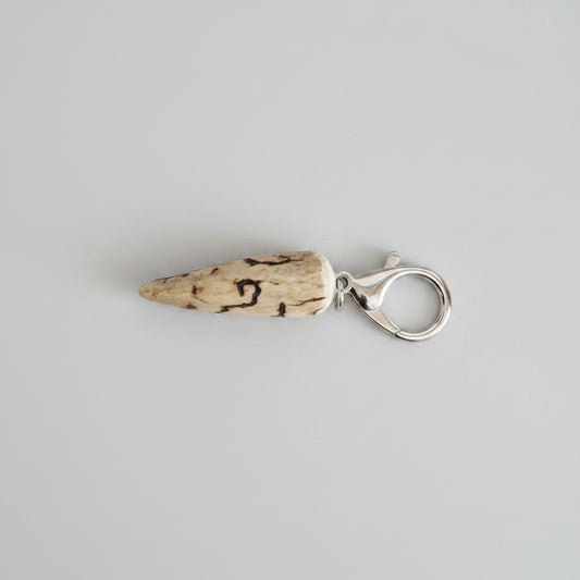 Deer antler tip with dark strike keychain with silver clasp on a gray background
