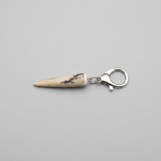 Deer antler tip keychain with silver clasp on a gray background