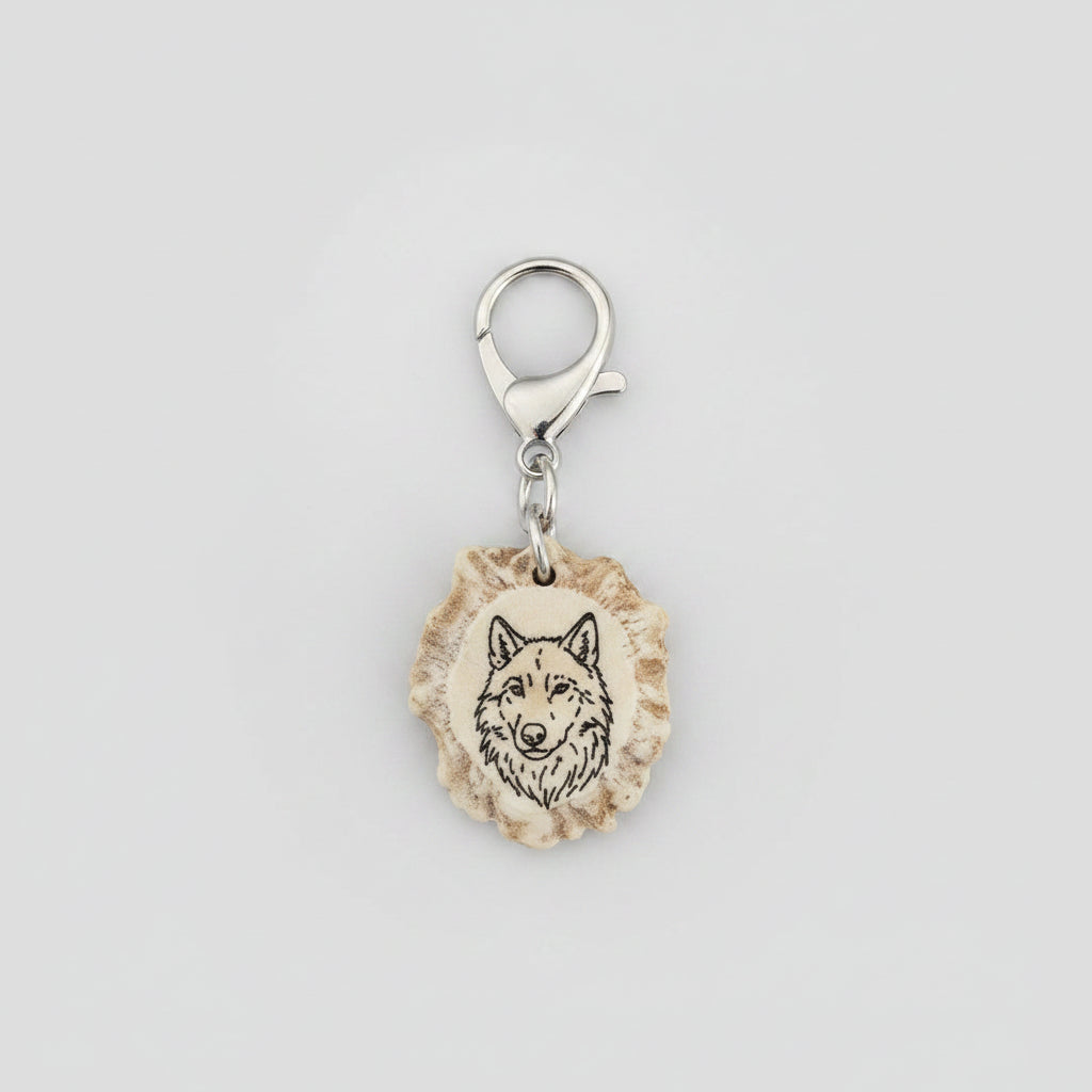 Wolf engraved on a deer antler keychain charm on a gray background
