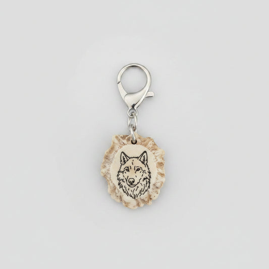 Wolf engraved on a deer antler keychain charm on a gray background