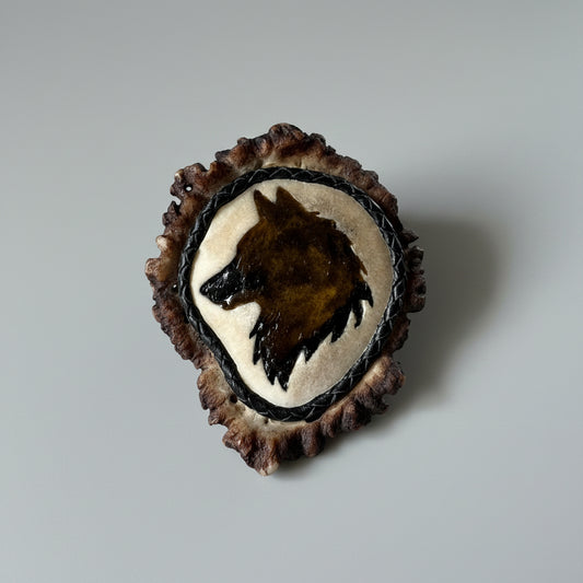 decorative elk antler cornet with a wolf head carved and inlayed on a gray background