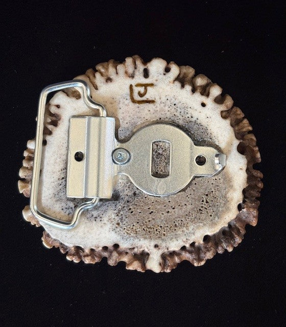 Back view of the Elk antler belt buckle with a bear engraved and polished on a black background