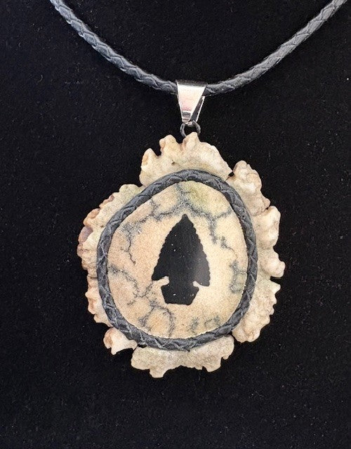 Necklace with a pendant featuring an arrowhead design on a black background