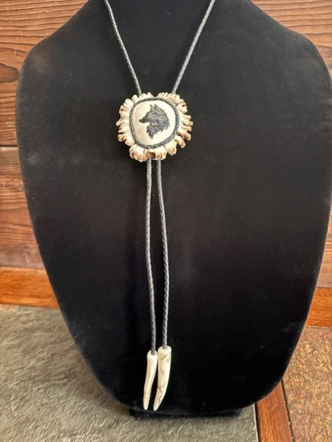 Bolo tie with a wolf design on a black mannequin bust against a wooden background