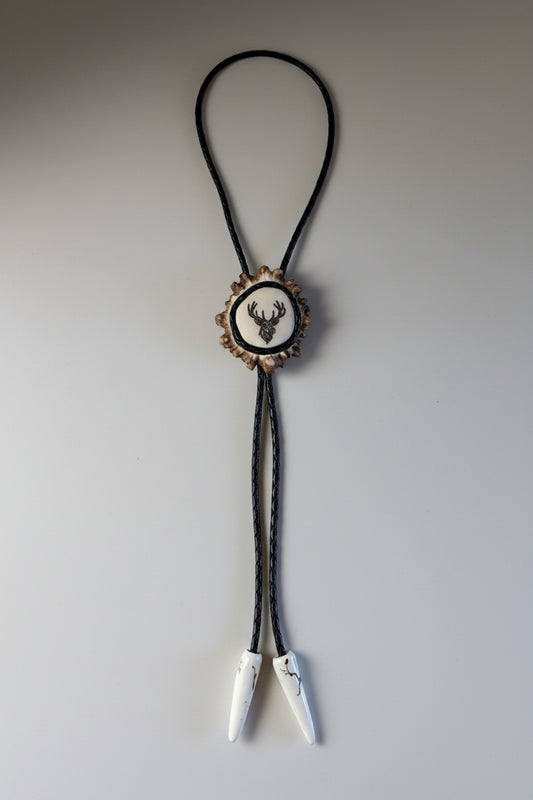 engraved elk bolo tie on a moose antler cornet on a gray background