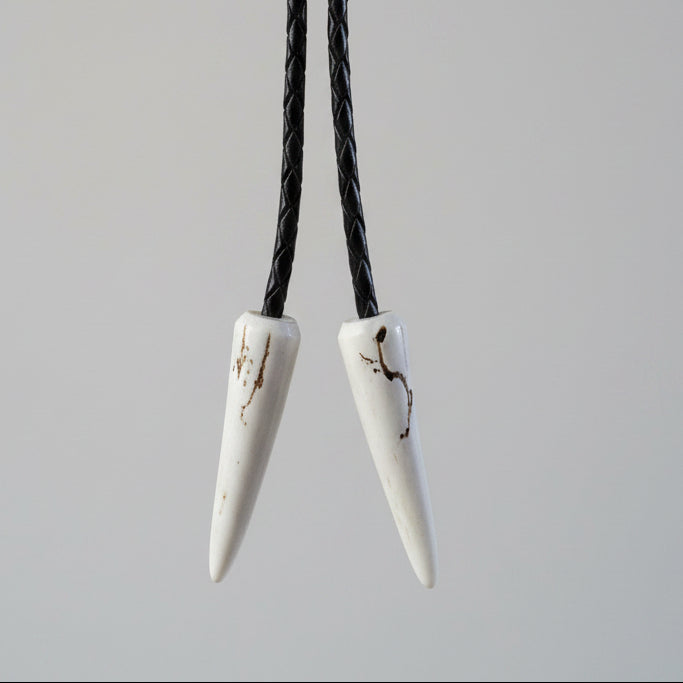 deer antler tips decorated at the end of the leather cord on a gray backgroud