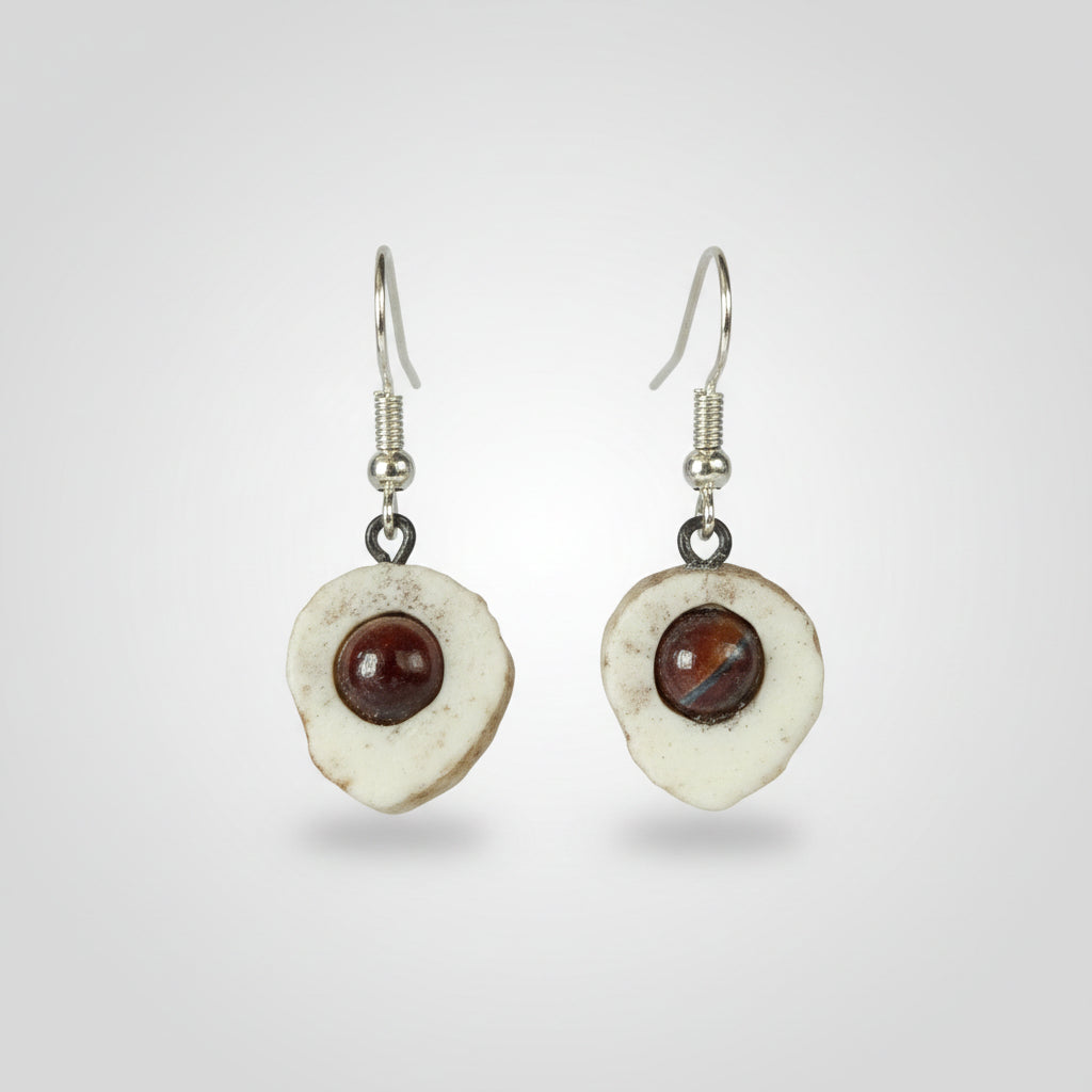 Natural deer antler of a pair of earrings with circular designs and embedded semi precious gem on gray background