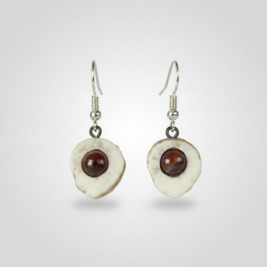 Natural deer antler of a pair of earrings with circular designs and embedded semi precious gem on gray background