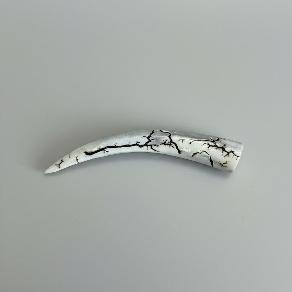 side view of the Natural deer antler comfort tine polished and decorated with strikes on a gray background