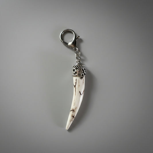 Polished deer antler keychain on a gray background