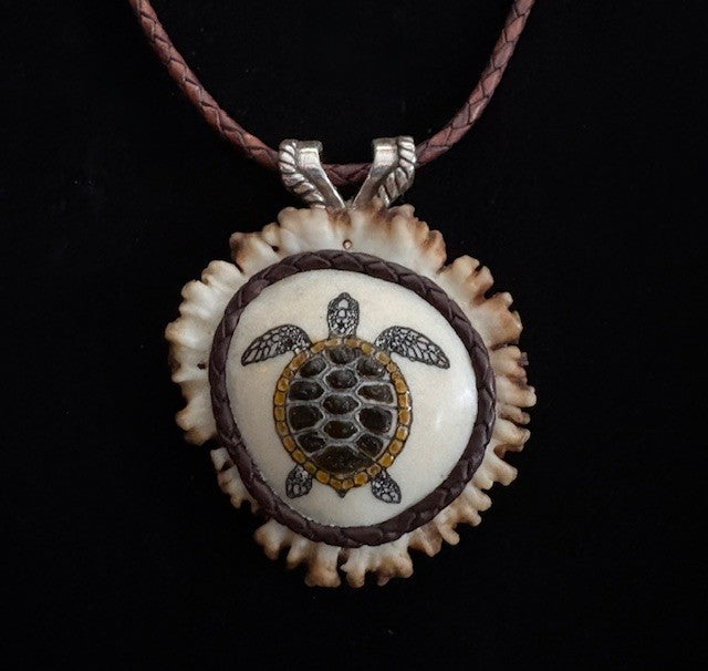 Tortoiseshell turtle pendant on a leather cord against a black background