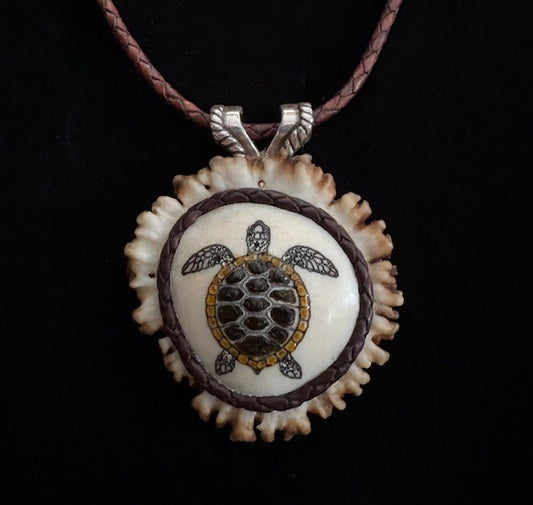 Tortoiseshell turtle pendant on a leather cord against a black background
