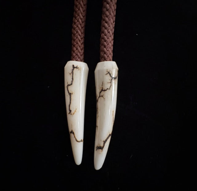 Antler tips at the end of the cords of the bolo tie on a black background