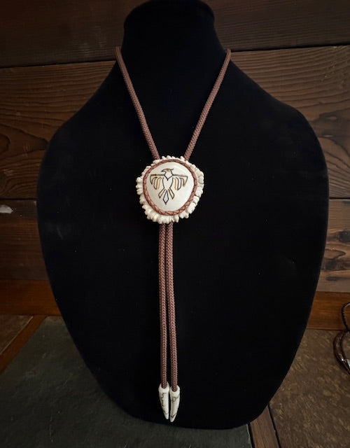 Bolo tie with a thunderbird on a black mannequin bust against a wooden background