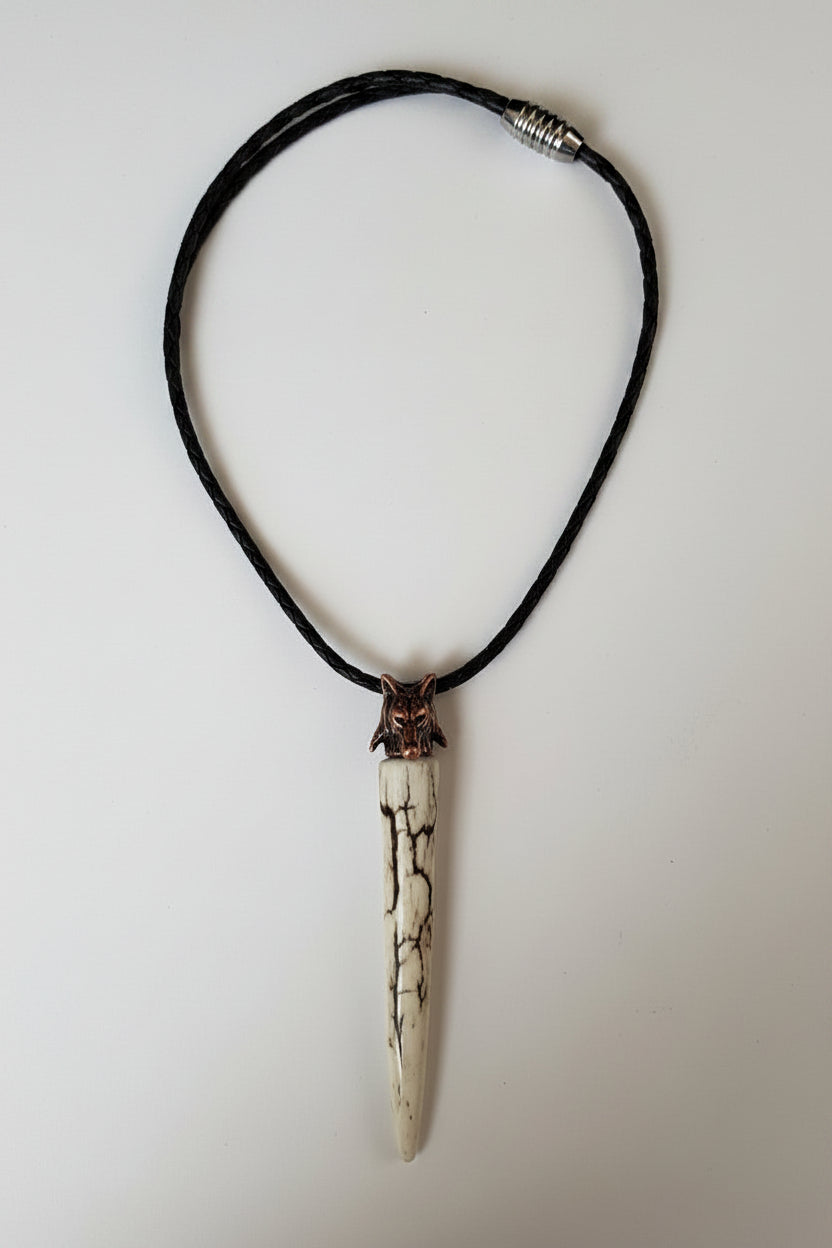 Deer antler tips necklace polished and with black strike attached to a metal wolf head with a black leather cord on a gray background